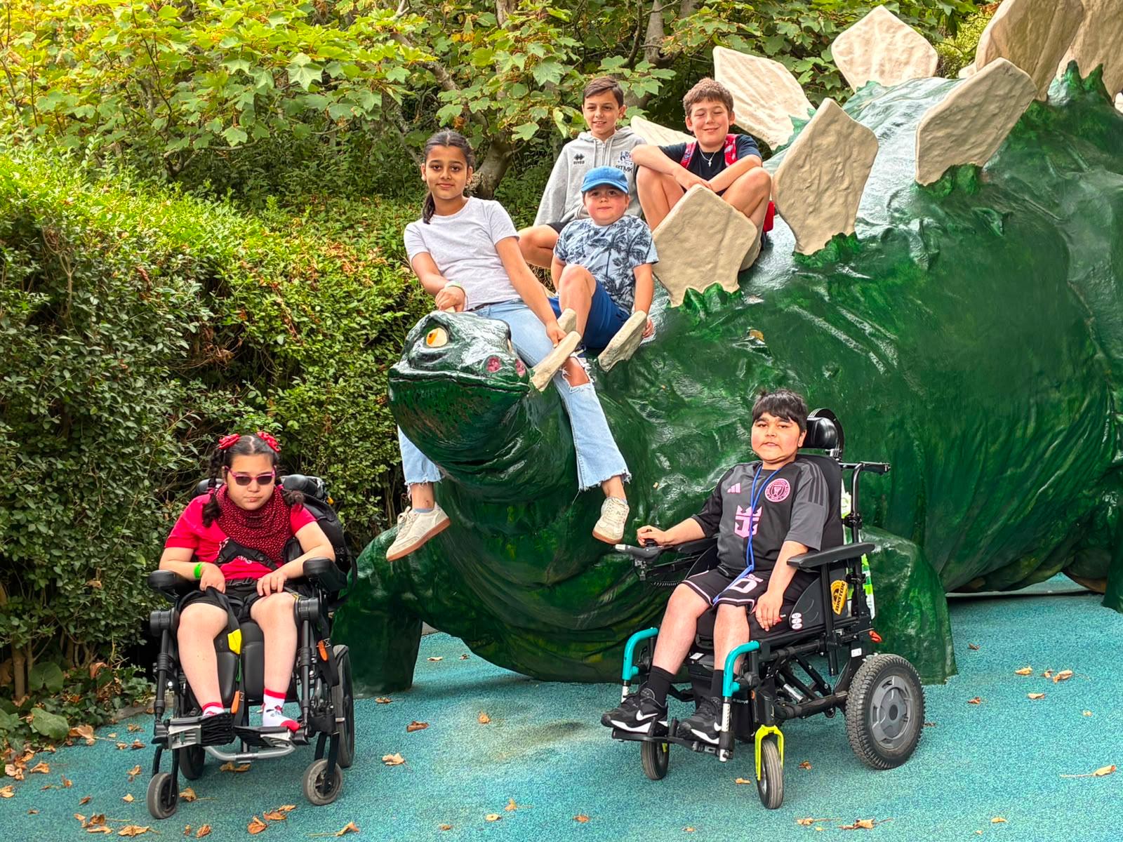 Children posing on a dinosaur statue on a Jumbulance day out